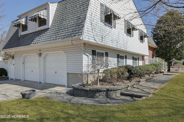 view of side of home featuring driveway, a garage, and roof with shingles