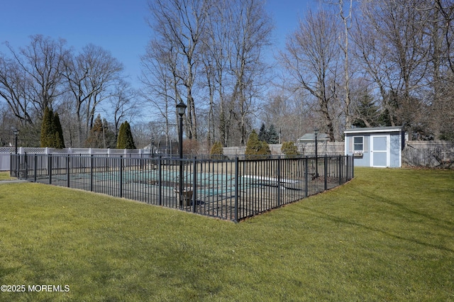 view of swimming pool with a shed, fence, a yard, an outdoor structure, and a fenced in pool