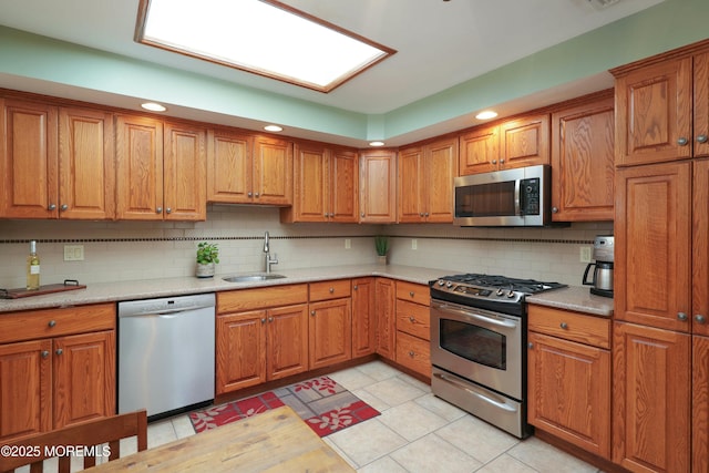 kitchen featuring a sink, stainless steel appliances, tasteful backsplash, and brown cabinetry