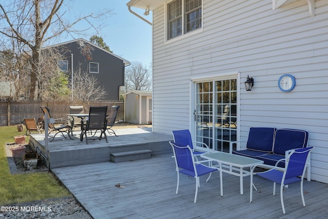 deck with a storage shed, an outbuilding, outdoor dining space, and fence