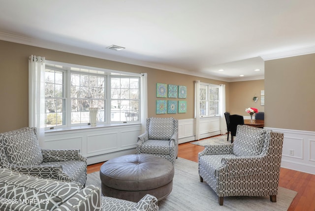 living room with a baseboard heating unit, wood finished floors, and crown molding