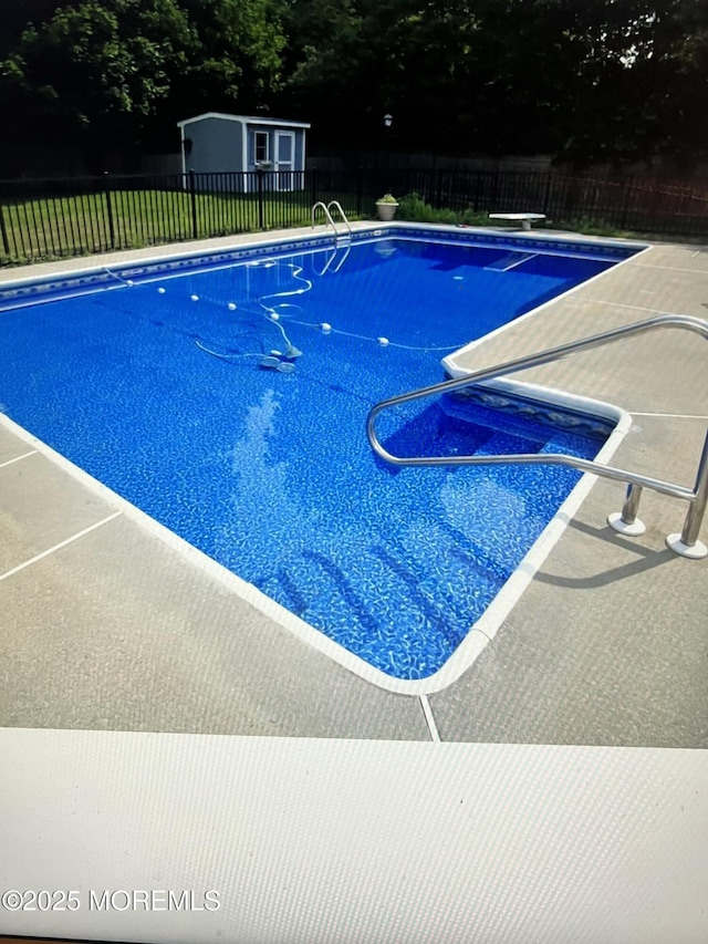 view of swimming pool featuring an outbuilding, a fenced in pool, a patio, and a fenced backyard