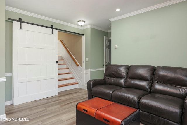 living area featuring stairs, a barn door, ornamental molding, recessed lighting, and light wood-style flooring