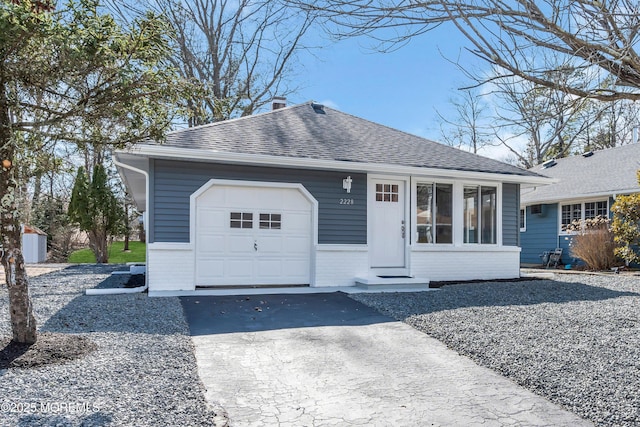 ranch-style home featuring an attached garage, a chimney, a shingled roof, aphalt driveway, and brick siding