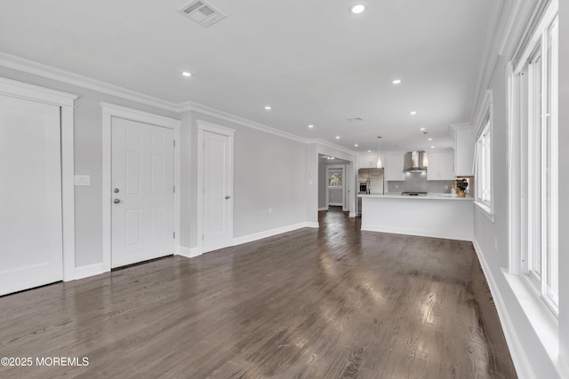 unfurnished living room with visible vents, dark wood-type flooring, recessed lighting, crown molding, and baseboards