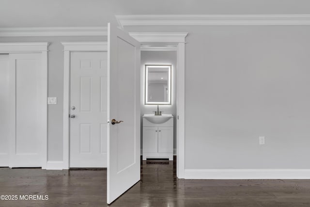 interior space featuring dark wood-style floors, crown molding, baseboards, and a sink