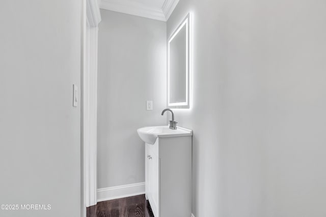 bathroom featuring vanity, wood finished floors, baseboards, and ornamental molding