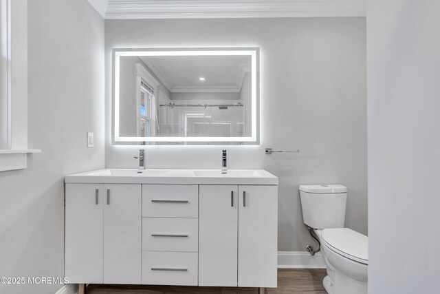 bathroom featuring ornamental molding, toilet, baseboards, and a sink