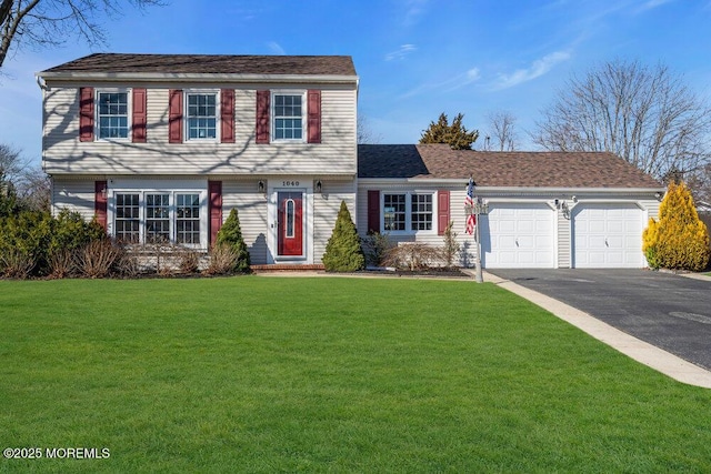 colonial home featuring aphalt driveway, a garage, and a front yard