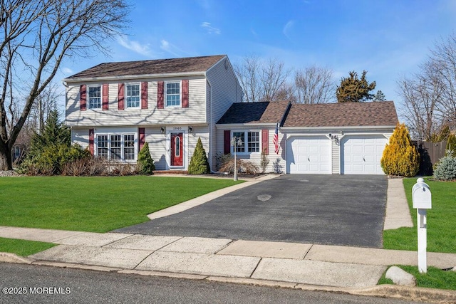 colonial-style house with driveway, an attached garage, and a front yard