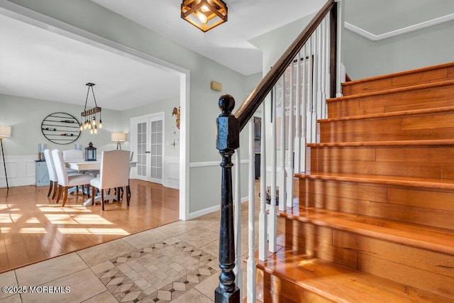 interior space featuring tile patterned floors, a decorative wall, french doors, and a wainscoted wall