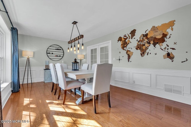 dining room featuring a decorative wall, light wood-style floors, and visible vents