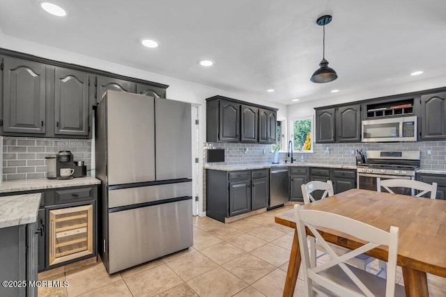 kitchen with light tile patterned floors, stainless steel appliances, light countertops, decorative light fixtures, and backsplash