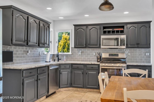 kitchen with a sink, backsplash, appliances with stainless steel finishes, and gray cabinets