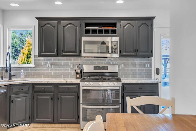 kitchen with a sink, backsplash, appliances with stainless steel finishes, and gray cabinets