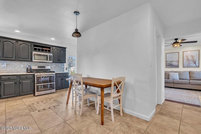 kitchen with backsplash, light countertops, light tile patterned floors, gray cabinets, and appliances with stainless steel finishes