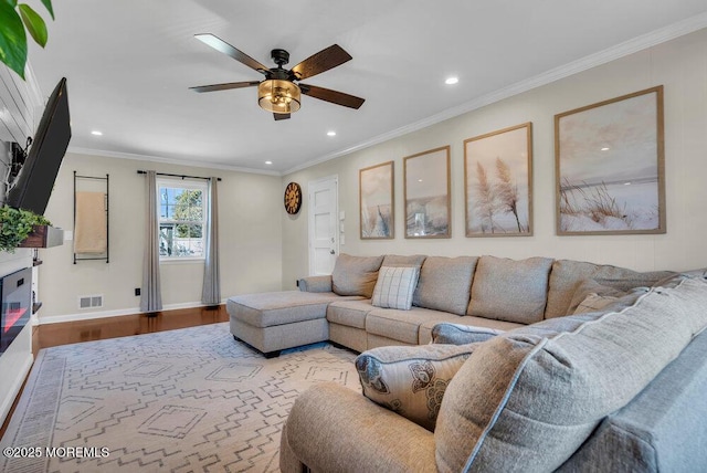 living area with wood finished floors, visible vents, baseboards, recessed lighting, and crown molding