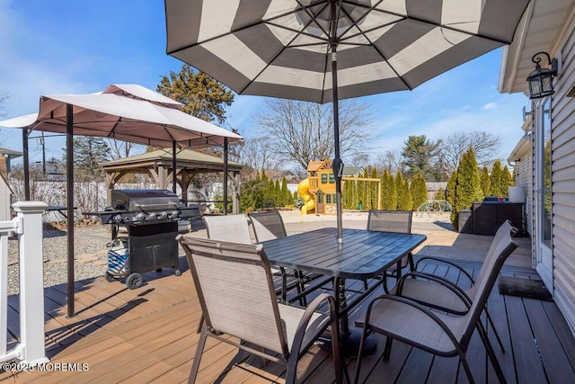 deck with grilling area, outdoor dining area, and a playground