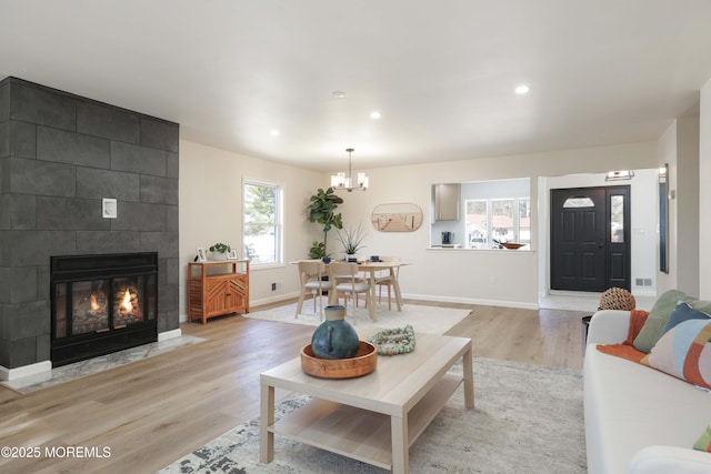 living room with recessed lighting, a large fireplace, light wood finished floors, baseboards, and a chandelier