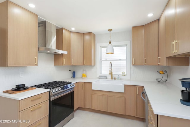 kitchen featuring stainless steel gas stove, light brown cabinetry, a sink, wall chimney range hood, and light countertops