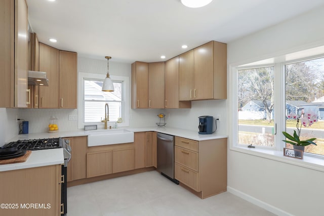 kitchen featuring a sink, hanging light fixtures, light countertops, stainless steel appliances, and under cabinet range hood