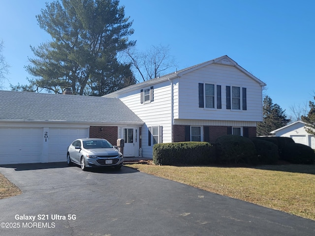 view of front of home with aphalt driveway, a front lawn, brick siding, and an attached garage