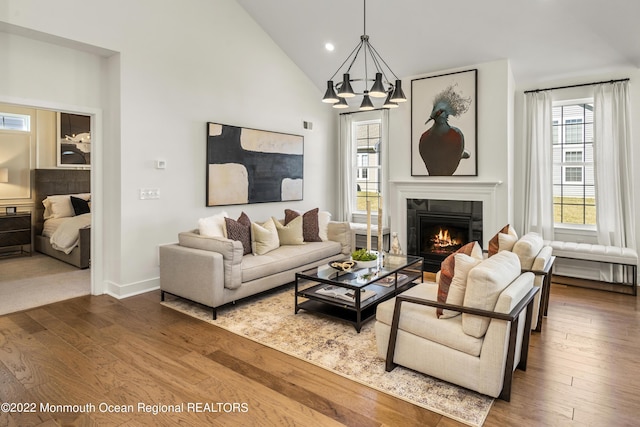 living room featuring high vaulted ceiling, a notable chandelier, dark wood-type flooring, and a fireplace