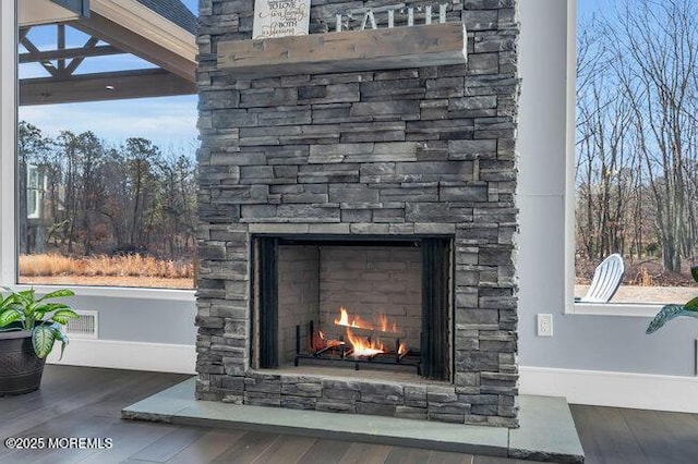 details with visible vents, an outdoor stone fireplace, baseboards, and wood finished floors