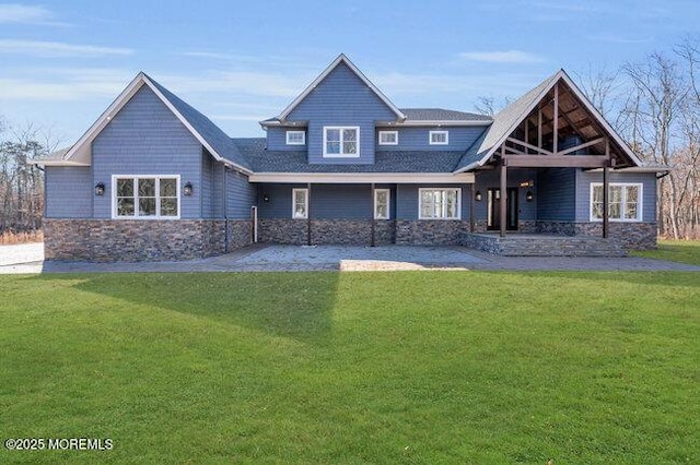 rear view of house featuring stone siding and a yard