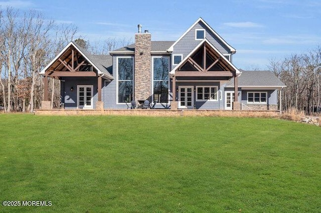 rear view of property with french doors, a lawn, and a chimney