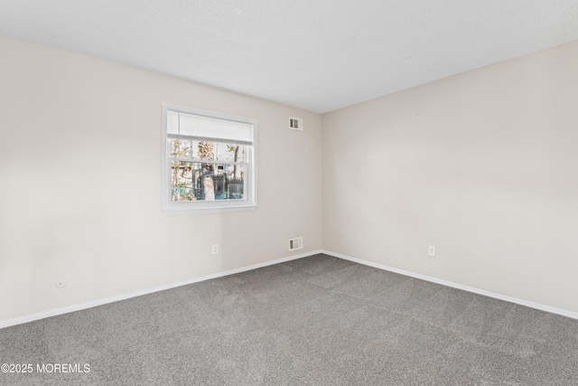 carpeted empty room featuring visible vents, baseboards, and a textured ceiling