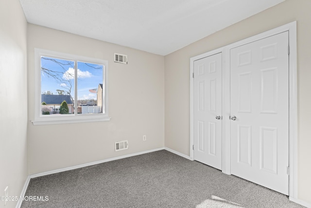 unfurnished bedroom featuring visible vents, baseboards, and carpet