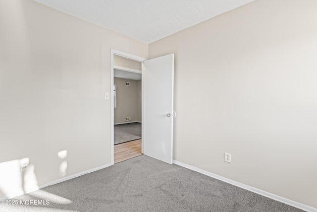 empty room featuring a textured ceiling, baseboards, and carpet