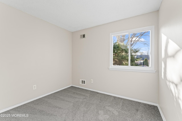 carpeted empty room with visible vents, baseboards, and a textured ceiling