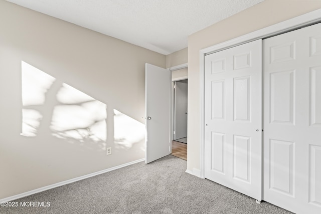 unfurnished bedroom with a closet, baseboards, a textured ceiling, and carpet flooring