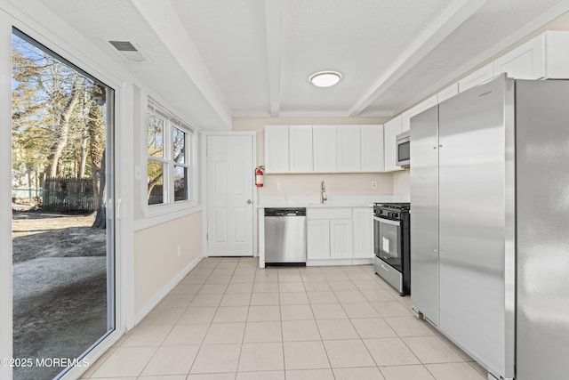 kitchen featuring a sink, stainless steel appliances, beamed ceiling, and white cabinets