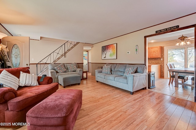 living area with stairway, light wood-style floors, and a ceiling fan