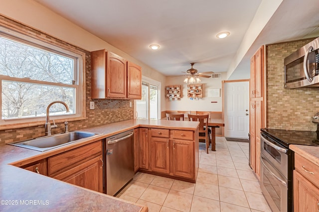 kitchen with light tile patterned floors, visible vents, a peninsula, a sink, and appliances with stainless steel finishes