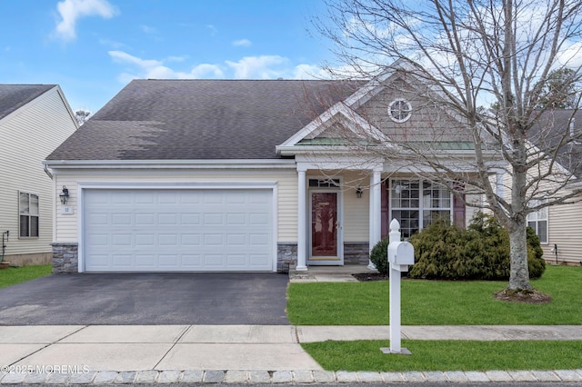 view of front of house with a front yard, an attached garage, stone siding, and roof with shingles