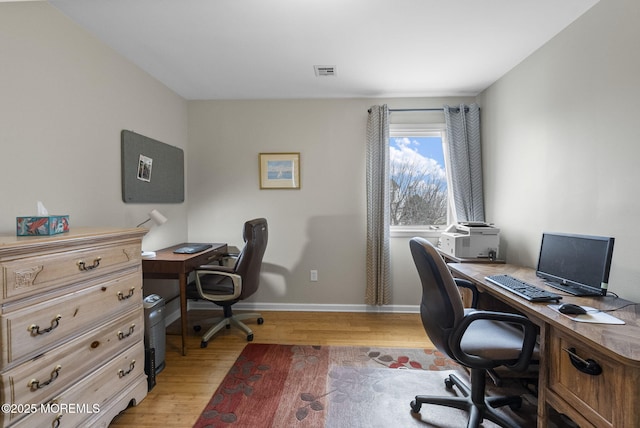 office space with light wood finished floors, visible vents, and baseboards