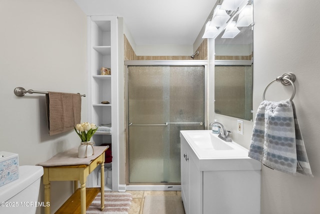 bathroom with vanity, toilet, a stall shower, and built in shelves