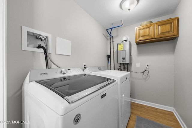 laundry room with baseboards, light wood-type flooring, water heater, cabinet space, and independent washer and dryer