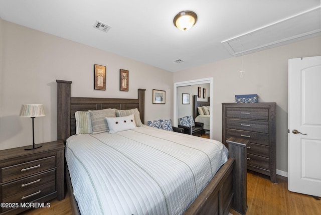 bedroom with visible vents, attic access, a closet, and light wood finished floors