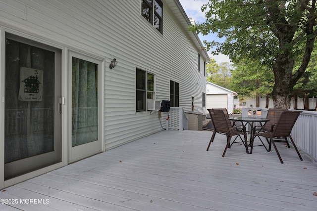 wooden deck featuring outdoor dining area and an outbuilding