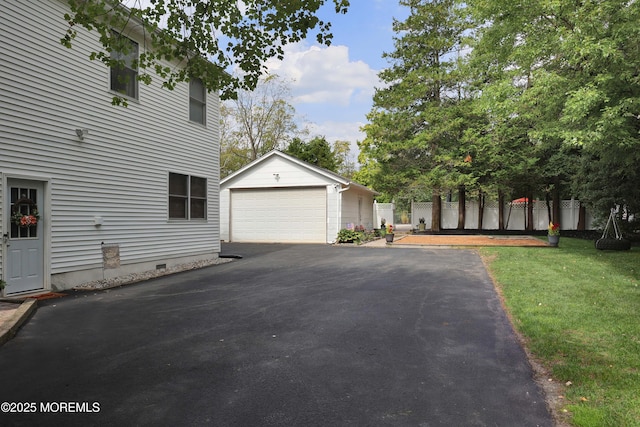 view of side of home featuring an outbuilding, a lawn, a detached garage, fence, and crawl space