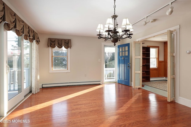 unfurnished dining area with a wealth of natural light, a baseboard heating unit, and hardwood / wood-style floors