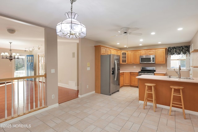 kitchen featuring recessed lighting, a sink, stainless steel appliances, light countertops, and glass insert cabinets