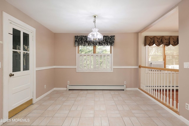 empty room featuring a wealth of natural light, baseboard heating, and an inviting chandelier