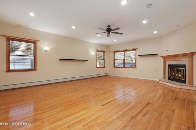 unfurnished living room featuring light wood-type flooring, a baseboard radiator, a glass covered fireplace, and recessed lighting