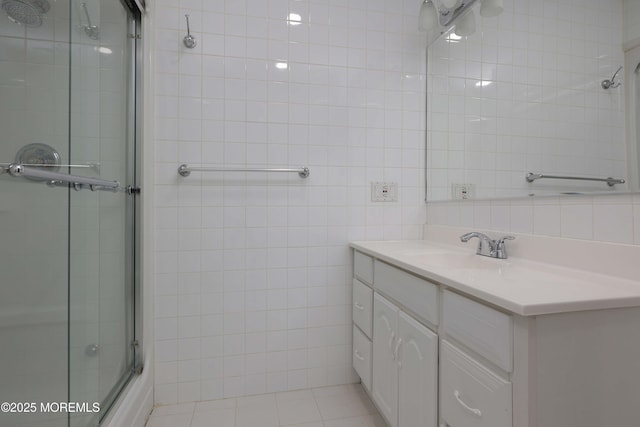 bathroom featuring tile patterned flooring, tile walls, vanity, and a tile shower